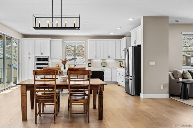 dining space with plenty of natural light, an inviting chandelier, and light hardwood / wood-style flooring