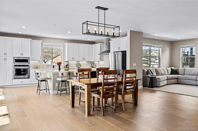 dining space with light hardwood / wood-style flooring and an inviting chandelier