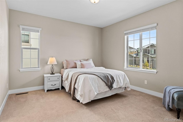 bedroom with multiple windows and light carpet