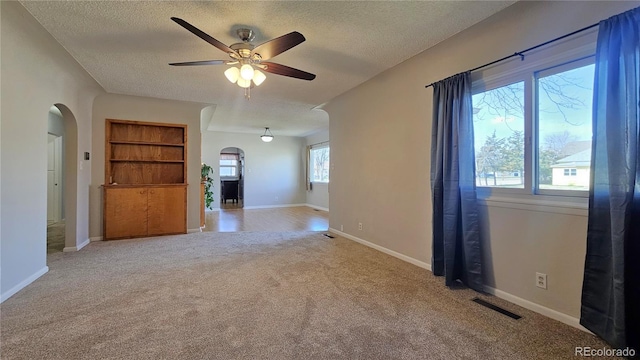 315 W 5th St, Julesburg, CO 80737 - empty room featuring a textured ceiling, visible vents, ceiling fan, arched walkways, and carpet