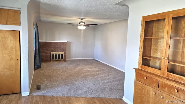 315 W 5th St, Julesburg, CO 80737 - unfurnished living room featuring baseboards, a fireplace, a textured ceiling, ceiling fan, and wood finished floors
