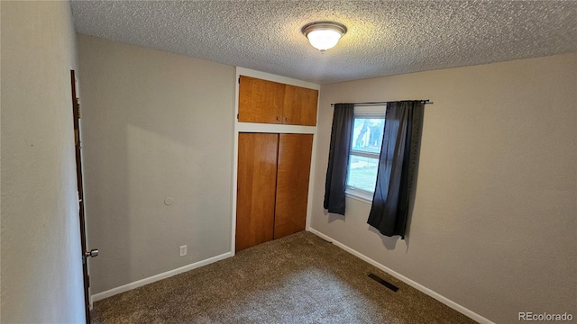 315 W 5th St, Julesburg, CO 80737 - unfurnished bedroom featuring a textured ceiling, a closet, visible vents, dark colored carpet, and baseboards