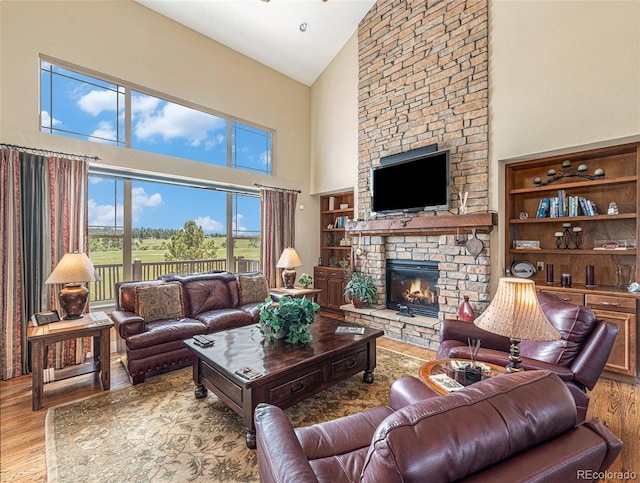 living room with high vaulted ceiling, wood finished floors, and a stone fireplace