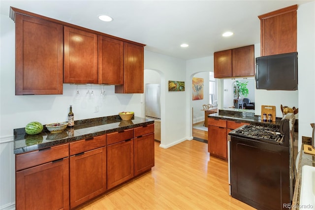 kitchen featuring black range oven, stainless steel refrigerator, and light hardwood / wood-style flooring