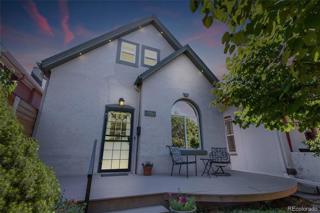 back house at dusk with a wooden deck