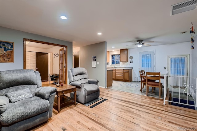 living room featuring light hardwood / wood-style floors, sink, and ceiling fan