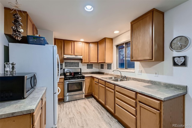 kitchen with sink, backsplash, stainless steel gas range, and light wood-type flooring