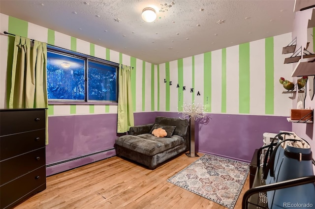 bedroom with a baseboard radiator, light wood-type flooring, and a textured ceiling