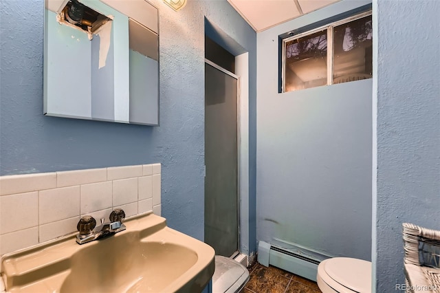 bathroom featuring toilet, a baseboard radiator, decorative backsplash, sink, and a shower with door