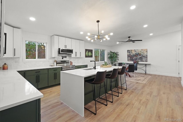 3025 Ivanhoe St, Denver, CO 80207 - kitchen with appliances with stainless steel finishes, a chandelier, light countertops, backsplash, and a breakfast bar area