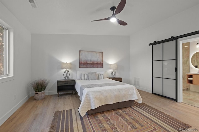 3025 Ivanhoe St, Denver, CO 80207 - bedroom featuring a barn door, wood finished floors, ensuite bath, and a ceiling fan