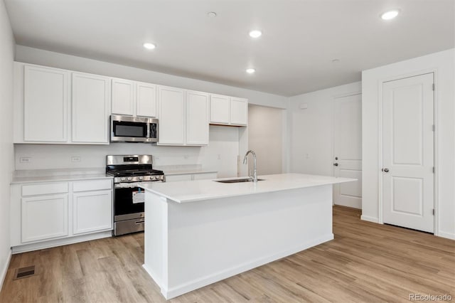 19110 E 96th Pl, Commerce City, CO 80022 - kitchen with appliances with stainless steel finishes, a sink, light wood finished floors, white cabinetry, and light countertops
