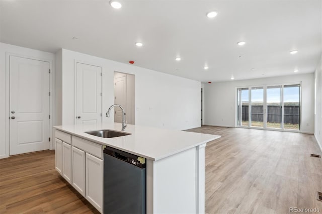 19110 E 96th Pl, Commerce City, CO 80022 - kitchen with dishwashing machine, a sink, light wood-style floors, a center island with sink, and white cabinetry