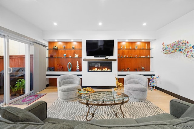 living room featuring built in shelves and light hardwood / wood-style flooring