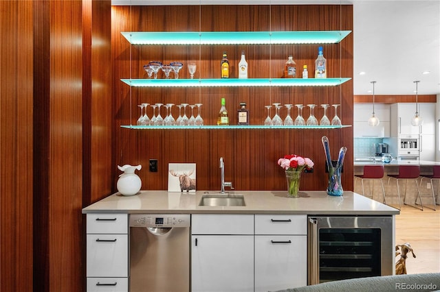 bar with pendant lighting, dishwasher, sink, wine cooler, and white cabinetry