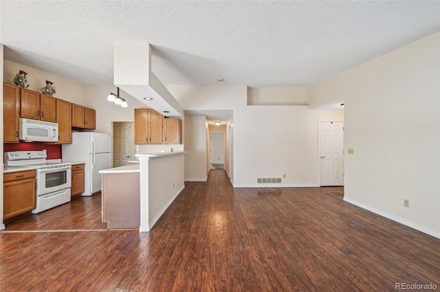 11565 Decatur St Unit 7D, Denver, CO 80234 - kitchen with white appliances, light countertops, a peninsula, dark wood-style floors, and brown cabinets