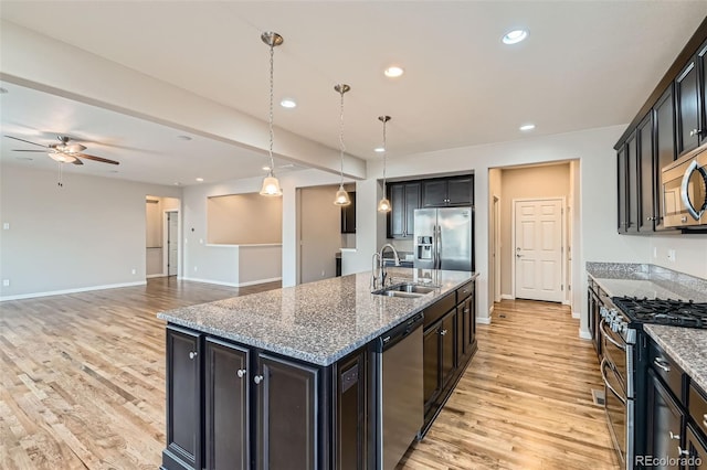 kitchen featuring appliances with stainless steel finishes, hanging light fixtures, an island with sink, ceiling fan, and sink