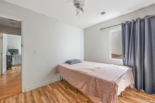 15627 E 51st Dr, Denver, CO 80239 - bedroom with a textured ceiling, wood finished floors, visible vents, and baseboards
