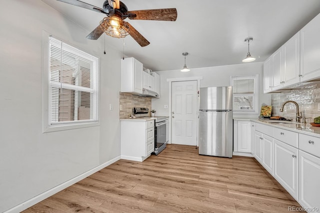 kitchen with appliances with stainless steel finishes, pendant lighting, backsplash, and white cabinetry