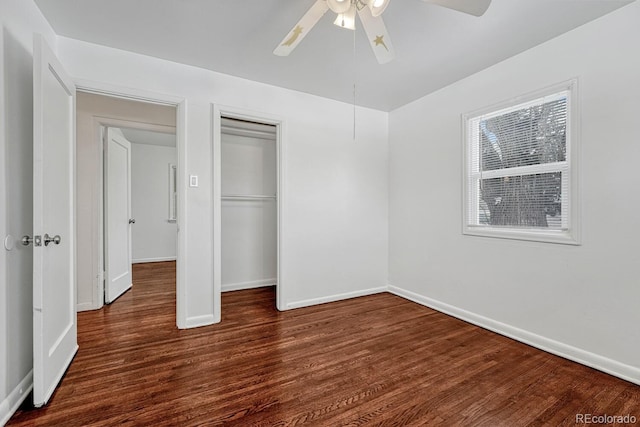 unfurnished bedroom with ceiling fan, multiple windows, dark hardwood / wood-style floors, and a closet