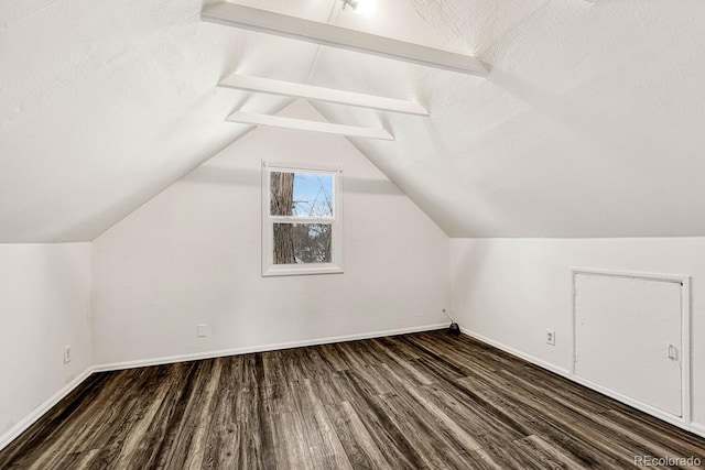 additional living space with vaulted ceiling with beams, dark wood-type flooring, and a textured ceiling