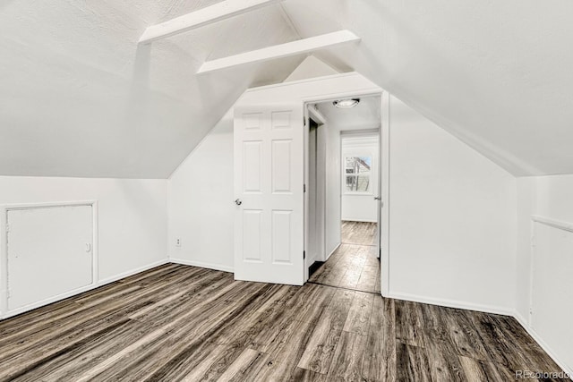 bonus room with a textured ceiling, dark hardwood / wood-style flooring, and lofted ceiling