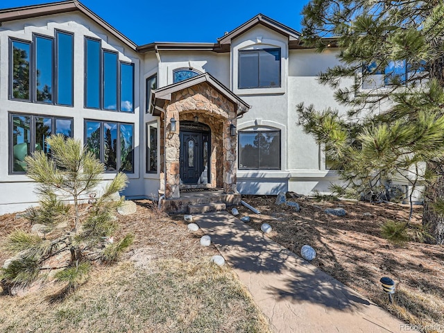 view of front of house featuring stone siding and stucco siding