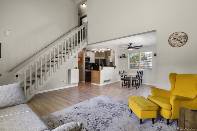 living room with visible vents, stairway, a ceiling fan, and wood finished floors