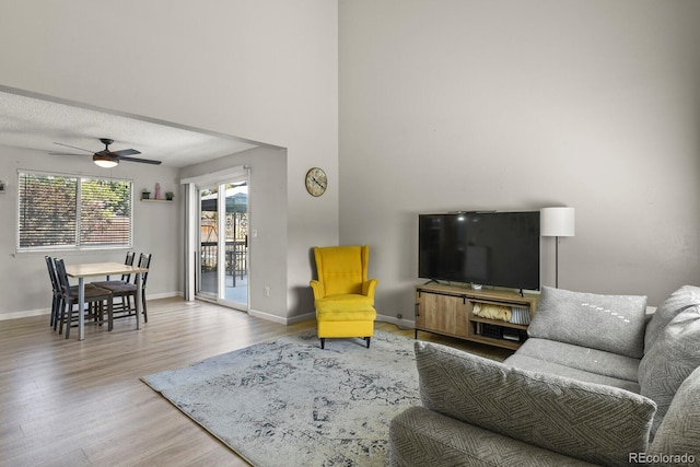 living area featuring baseboards, a textured ceiling, wood finished floors, and a ceiling fan