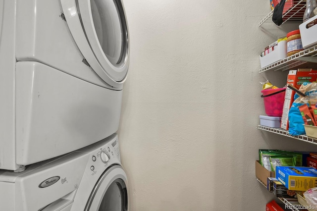 laundry area with laundry area, stacked washer / dryer, and a textured wall