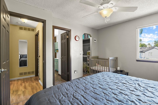 bedroom with visible vents, a textured ceiling, and wood finished floors