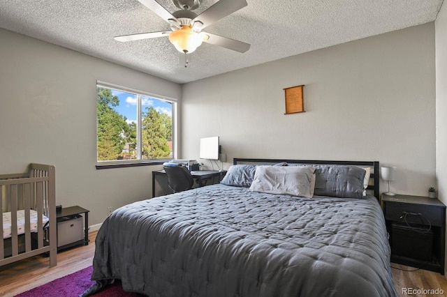 bedroom with baseboards, a textured ceiling, ceiling fan, and wood finished floors