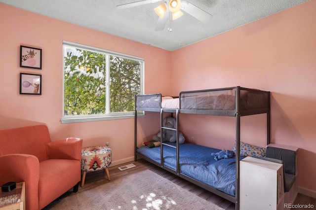 bedroom with baseboards, wood finished floors, visible vents, and a textured ceiling