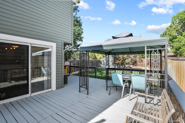 wooden deck featuring a gazebo, outdoor dining area, and a fenced backyard