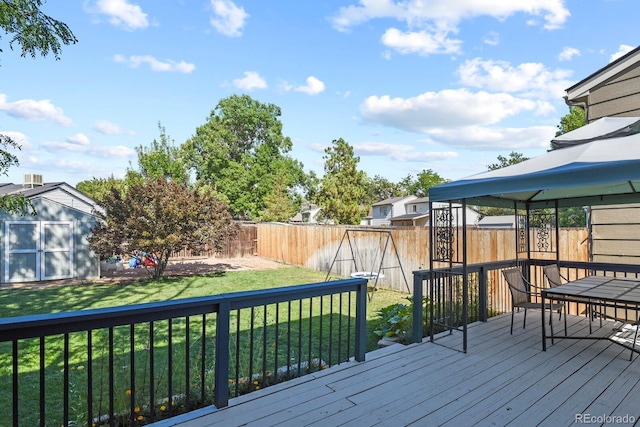 wooden terrace with a gazebo, a storage unit, an outbuilding, and a yard