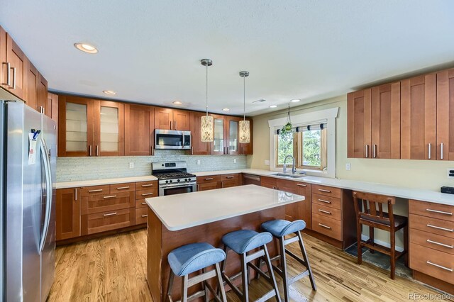 540 Ithaca Dr, Boulder, CO 80305 - kitchen with stainless steel appliances, brown cabinetry, light wood-style flooring, a breakfast bar area, and light countertops