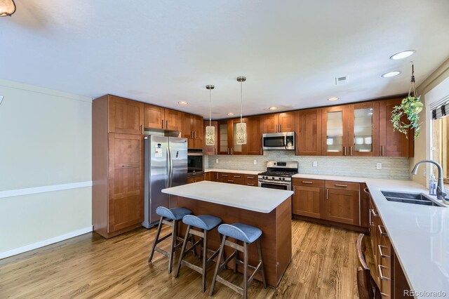 540 Ithaca Dr, Boulder, CO 80305 - kitchen with stainless steel appliances, a kitchen bar, light wood-style flooring, backsplash, and a kitchen island