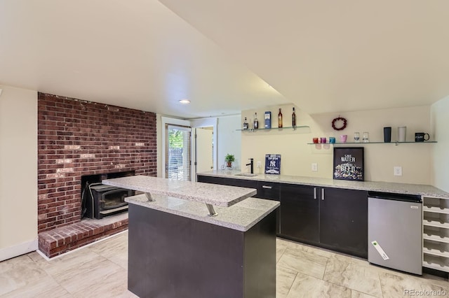 540 Ithaca Dr, Boulder, CO 80305 - kitchen featuring refrigerator, a wood stove, a kitchen island, and light stone countertops