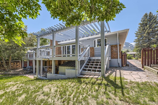 540 Ithaca Dr, Boulder, CO 80305 - rear view of property featuring brick siding, a wooden deck, a pergola, and a lawn
