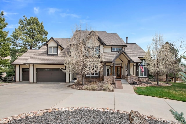 view of front of house with stone siding, driveway, a tile roof, a garage, and stucco siding