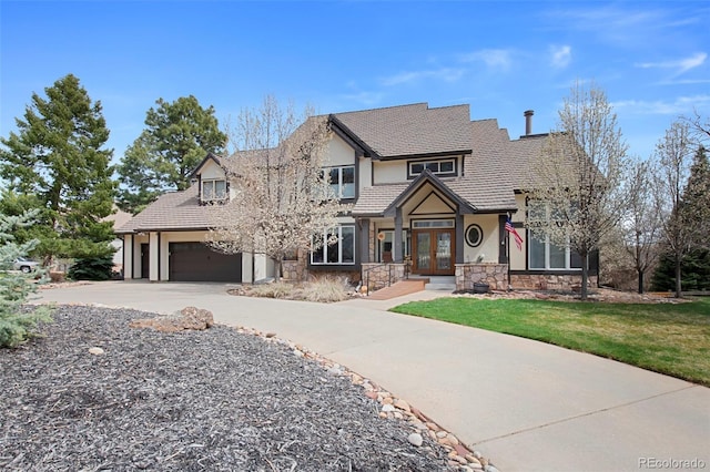 craftsman inspired home with stone siding, french doors, a garage, stucco siding, and concrete driveway