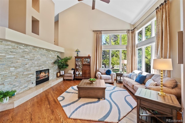 living room with a fireplace, high vaulted ceiling, a ceiling fan, and wood finished floors