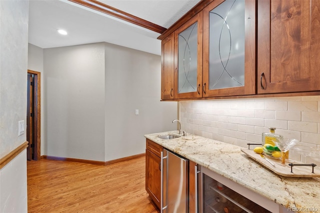 kitchen with fridge, a sink, light wood-type flooring, backsplash, and light stone countertops