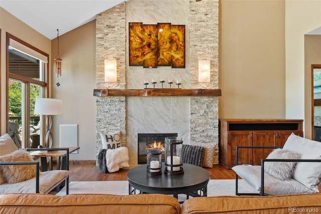 living room with a large fireplace, wood finished floors, baseboards, and high vaulted ceiling