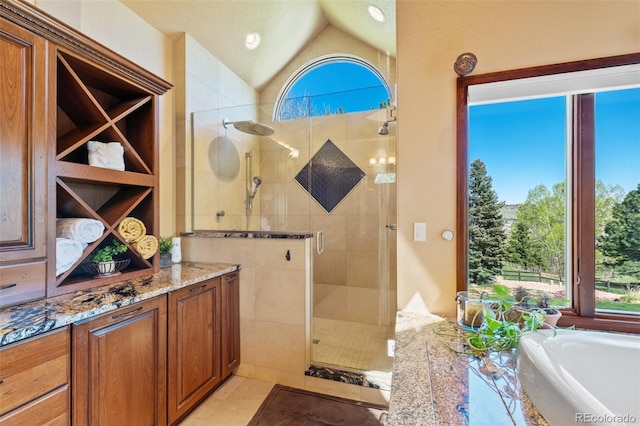 bathroom featuring a stall shower, tile patterned floors, a bath, vaulted ceiling, and vanity
