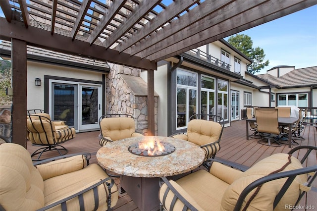 wooden terrace with an outdoor fire pit, outdoor dining area, and a pergola