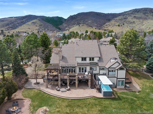 rear view of property with stucco siding, a pergola, a chimney, a yard, and a deck with mountain view