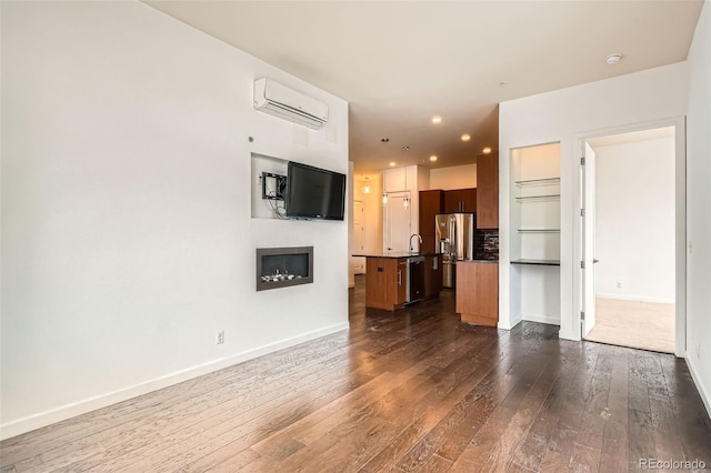 336 E 1st Ave Unit 200, Denver, CO 80203 - unfurnished living room featuring a wall mounted air conditioner, a glass covered fireplace, dark wood-style flooring, and recessed lighting