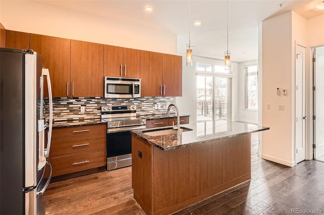 336 E 1st Ave Unit 200, Denver, CO 80203 - kitchen featuring stainless steel appliances, brown cabinetry, dark wood finished floors, decorative backsplash, and dark stone counters