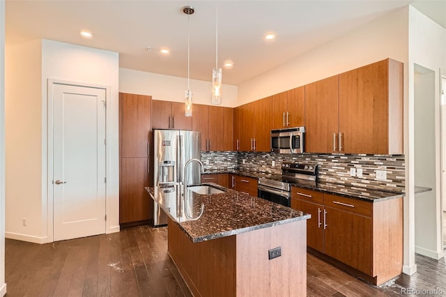 336 E 1st Ave Unit 200, Denver, CO 80203 - kitchen with appliances with stainless steel finishes, brown cabinetry, dark stone countertops, dark wood-style flooring, and recessed lighting